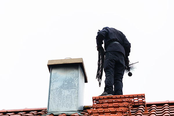 Man on rooftop working on chimney.