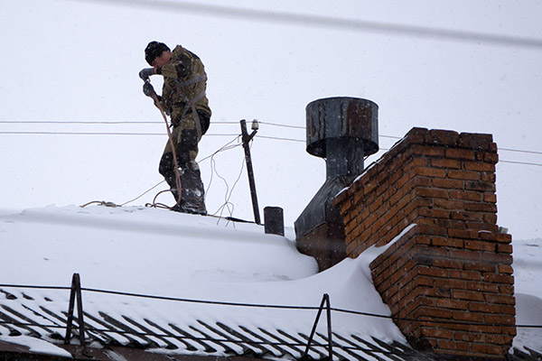 Chimney sweep on wintery rooftop.