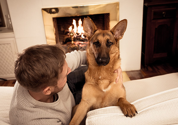 Man with dog at home near fireplace.