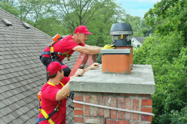 two vertical workers capping a chimney