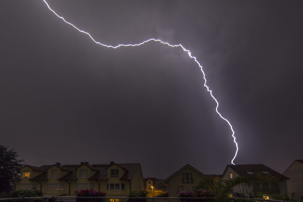 Image of lightning in the night hitting a house on the ground